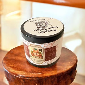 May include: A jar of Pumpkin Patch Tallow cream with a black lid sits on a small wooden stool. The label features a corgi illustration and text that reads "100% Organic" and "Nourishing & Hydrating For Face & Skin."