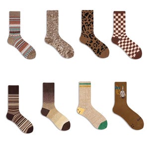 Könnte beinhalten: Acht Paar Socken mit verschiedenen Mustern und Farben. Zu den Designs gehören Streifen, Leopardenmuster, Schachbrettmuster und geometrische Muster. Die Farbpalette umfasst Braun, Beige und Grün. Die Socken sind auf weißem Hintergrund dargestellt.