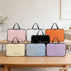 May include: A collection of laptop cases in various colors, including pink, white, orange, black, yellow, blue, and purple. Each case has a black handle and zipper, with the text "Quentin Cafe" printed on the front.