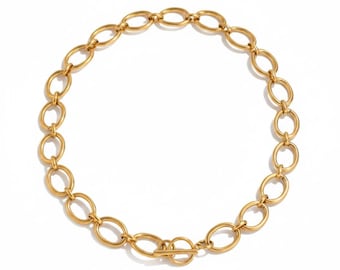May include: A gold-colored necklace featuring a series of oval-shaped links. The necklace has a toggle clasp closure. The jewelry is displayed on a white background. The necklace is a statement piece.