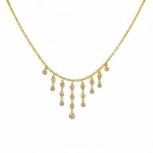 May include: A delicate gold necklace with a series of dangling clear gemstones. The necklace features a fine chain with multiple strands of gemstones cascading downwards. The gemstones are round and appear to be set in a bezel setting. The necklace is displayed against a white background.