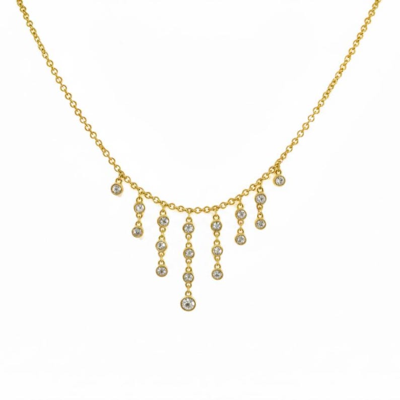 May include: A delicate gold necklace with a series of dangling clear gemstones. The necklace features a fine chain with multiple strands of gemstones cascading downwards. The gemstones are round and appear to be set in a bezel setting. The necklace is displayed against a white background.