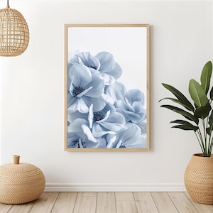 May include: A framed print featuring a close-up of light blue flowers with dark centers. The flowers are clustered together, filling the frame. The wooden frame adds a natural touch to the floral artwork, suitable for home decor.