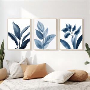 May include: Three framed botanical prints featuring blue leaf illustrations against a white background. The leaves vary in shape and arrangement, with a focus on the veins and textures. The frames are a light wood color, adding a natural touch to the artwork.