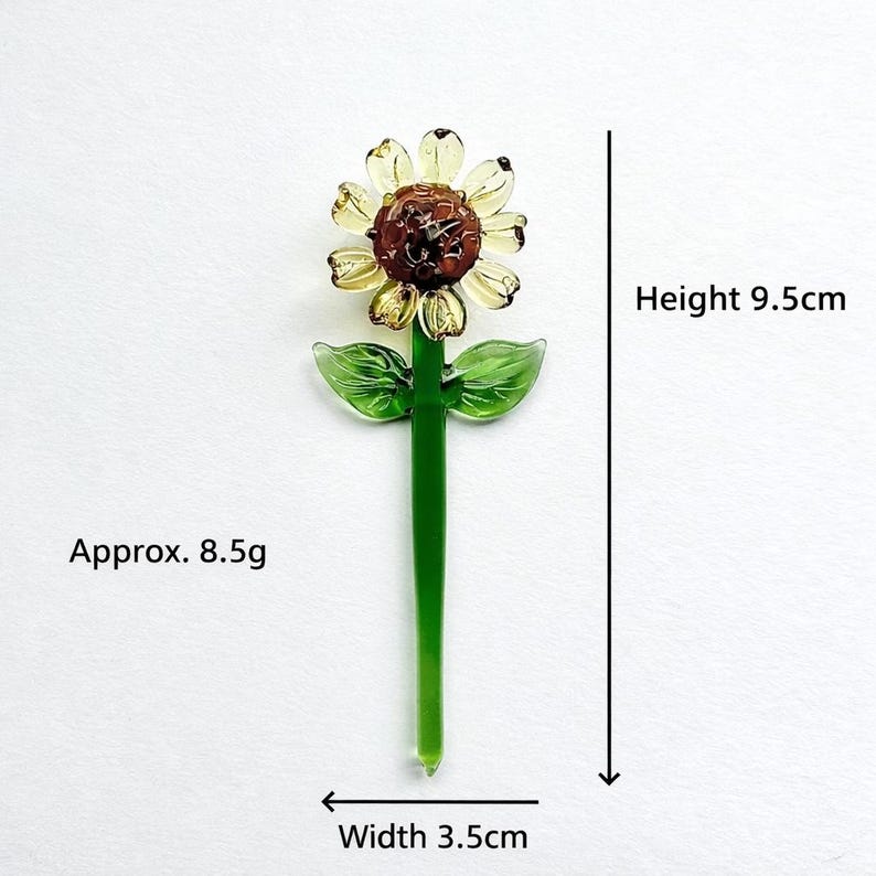 Puede incluir: Un girasol de cristal con centro marr&oacute;n, p&eacute;talos amarillos y tallo y hojas verdes. La altura es de 9,5 cm y el ancho de 3,5 cm. El peso es de aproximadamente 8,5 g. Un acento floral &uacute;nico.