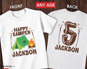 May include: White short or long sleeve shirt or bodysuit with a camping theme. The front of the shirt has a green tent, a campfire, and the text "Happy Camper" and "Jackson". The back of the shirt has a brown number 5 and the text "Jackson".