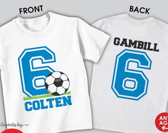 May include: White t-shirt with a blue number 6 and a soccer ball on the front. The back of the shirt has the name "GAMBILL" and the number 6 in blue. The shirt is available in short or long sleeve and can be a shirt or bodysuit.