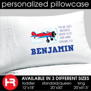 May include: A white pillowcase featuring a red and blue airplane graphic flying through clouds. The text reads: YOU ARE GOD'S MASTERPIECE CREATED TO DO GOOD WORKS. EPHESIANS 2:10, with the name BENJAMIN printed in large blue letters below the airplane.