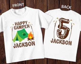 May include: Two white shirts showing front and back designs. The front features a green tent, a campfire, marshmallows on sticks, and the text "HAPPY CAMPER JACKSON". The back displays a large number 5 in a log texture with marshmallows and "JACKSON".