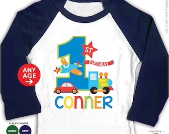 May include: A white long-sleeve shirt with a blue and white baseball design. The shirt has a blue number one with a green outline, a red car, a blue airplane, a green and yellow train, and the text "1st Birthday" and "Conner".