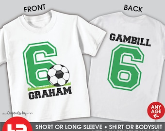 May include: White t-shirt with a green number 6 and a soccer ball on the front. The back of the shirt has the name "GAMBILL" and the number 6. The text "ANY AGE" is on the back of the shirt.