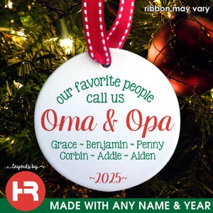 May include: White ceramic Christmas ornament with green and red text that reads "our favorite people call us Oma & Opa Grace ~ Benjamin ~ Penny Corbin ~ Addie ~ Aiden ~2025~"