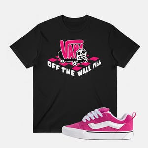 以下が含まれることがあります： スケートボードに乗ったスカルが描かれた、ピンクと白のVansグラフィックが特徴の黒いTシャツ。白い靴紐と白いサイドストライプが付いた、ピンクのスエードVans Old Skoolスニーカーも画像にあります。