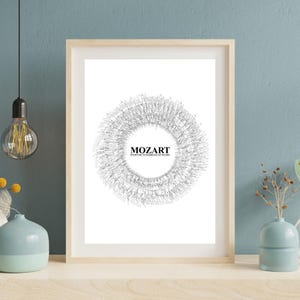 May include: A framed print featuring the name "MOZART" in a minimalist design. The artwork showcases a circular pattern of fine lines, creating a textured effect. The print is in a light wooden frame, suitable for home decor.
