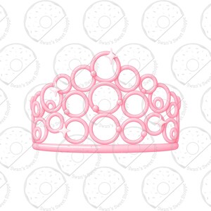 May include: A pink tiara with a series of connected circles and star accents. The tiara is a light pink color and is designed with a series of connected circles and star accents. The tiara is a decorative item.