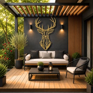 A gold-colored metal wall art piece shaped like a deer head, featuring an intricate cutout design of a forest with trees