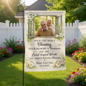 May include: A garden flag with a photograph of an older couple in a window, framed by flowers. The flag displays the text "Your Life Was a Blessing, Your Memory a Treasure, You Are Loved Beyond Words..." and "Mom And Dad, 11.9.2021."