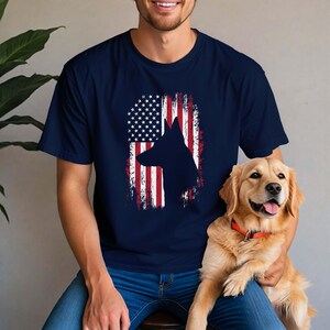 May include: Navy blue t-shirt featuring a distressed American flag design with a dog silhouette. The flag has red and white stripes with a field of white stars. The dog silhouette is black. The shirt is short-sleeved.