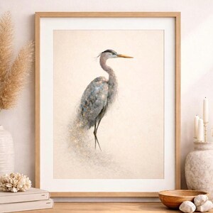 Könnte beinhalten: Gerahmter Kunstdruck mit einer detaillierten Illustration eines Graureihers. Der Vogel ist in Grau- und Blautönen mit gelbem Schnabel dargestellt, vor einem weichen, neutralen Hintergrund. Das Kunstwerk ist in einem hellen Holzrahmen gerahmt.