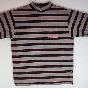 May include: A short-sleeved, striped t-shirt with a mock neck. The shirt features horizontal black and gray stripes with thin red lines. A pocket on the chest displays the word "VISION" in a stylized font. The shirt is laid flat.