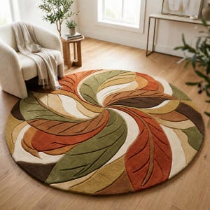 May include: A circular area rug featuring a repeating, swirling pattern of stylized leaves in shades of burnt orange, olive green, mustard yellow, dark brown, and cream. The design creates a radial, fan-like effect with carved textures.