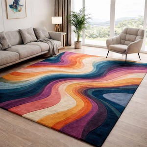 Könnte beinhalten: Ein großer, farbenfroher Teppich mit einem wellenförmigen, abstrakten Design. Der Teppich weist eine lebendige Farbpalette auf, darunter Schattierungen von Lila, Orange, Blau und Creme. Der Teppich befindet sich in einem Wohnzimmer und setzt ein klares Statement.