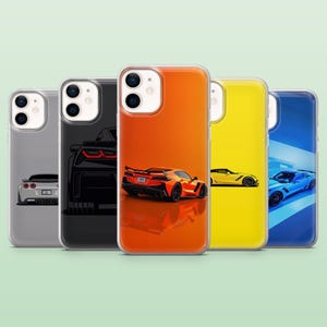 May include: Five phone cases displaying car designs in a row. The cases feature cars in grey, black, orange, yellow, and blue. Each case has a clear border and a glossy finish. The cases are designed for a mobile phone.