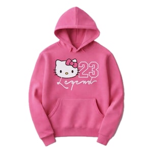 Pu&ograve; includere: Felpa con cappuccio rosa con grafica di un gatto dei cartoni animati, il numero 23 e la parola "Legend" in bianco. Ha una tasca a marsupio e un cappuccio con coulisse. Un capo casual e confortevole.
