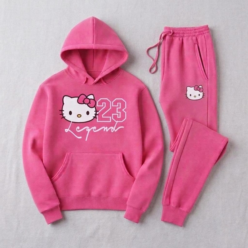 Pu&ograve; includere: Un completo tuta rosa acceso composto da una felpa con cappuccio e pantaloni abbinati. La felpa con cappuccio presenta una grafica di un gatto dei cartoni animati, il numero 23 e la parola "Legend". Anche i pantaloni hanno una piccola grafica di gatto.