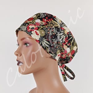 Può includere: Una cuffia chirurgica con sfondo nero e un denso motivo floreale nei toni del rosso, bianco e oro, accentuato da fogliame verde. La cuffia presenta una calotta arrotondata e due lacci in tessuto sul retro per una vestibilità regolabile.