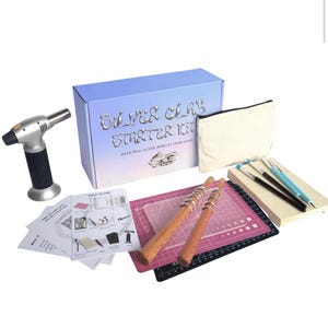 May include: A silver clay starter kit with a blue box, a torch, a canvas pouch, tools, and instructions. The box reads "Silver Clay Starter Kit" and "Make Real Silver Jewelry From Home."