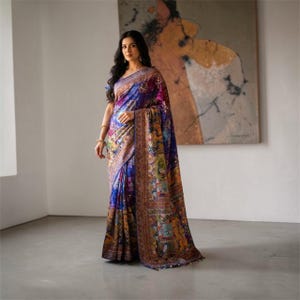 Peut inclure: Une femme porte un sari aux couleurs vives. Le sari présente un mélange de bleus, de violets et d'or, avec des motifs complexes et une bordure détaillée. Le tissu est drapé, mettant en valeur le vêtement indien traditionnel.