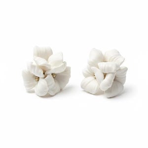 May include: Two white floral-shaped earrings. Each earring features multiple petals and a small, gold-colored accent in the center. The earrings are set against a white background, highlighting their delicate design.