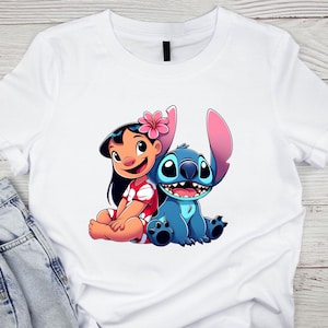 K&ouml;nnte beinhalten: Wei&szlig;es T-Shirt mit einer farbenfrohen Grafik von Lilo und Stitch. Lilo tr&auml;gt ein rotes Kleid mit wei&szlig;en Akzenten und eine rosa Blume. Stitch ist blau mit gro&szlig;en Ohren und einem fr&ouml;hlichen Gesichtsausdruck.
