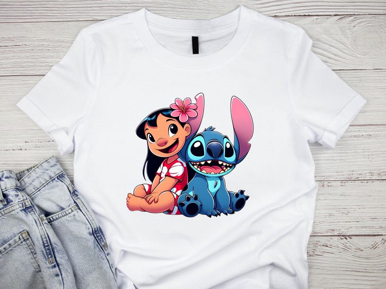 K&ouml;nnte beinhalten: Wei&szlig;es T-Shirt mit einer farbenfrohen Grafik von Lilo und Stitch. Lilo tr&auml;gt ein rotes Kleid mit wei&szlig;en Akzenten und eine rosa Blume. Stitch ist blau mit gro&szlig;en Ohren und einem fr&ouml;hlichen Gesichtsausdruck.