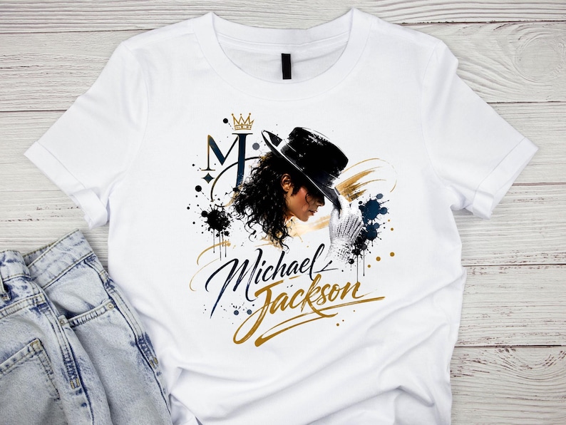 May include: White t-shirt featuring a graphic of Michael Jackson in profile, wearing a black hat and white glove. The design includes the letter "M" with a crown, and the name "Michael Jackson" in gold script.