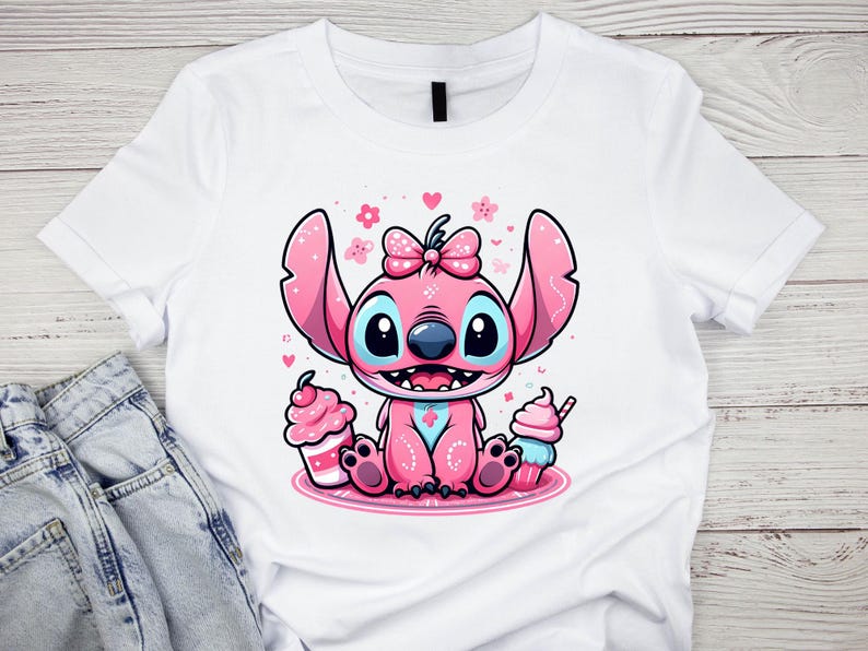 K&ouml;nnte beinhalten: Wei&szlig;es T-Shirt mit einem rosa Cartoon-Charakter-Design. Der Charakter hat gro&szlig;e Ohren, eine Schleife und blaue Augen, umgeben von Herzen und Blumen. Zwei Cupcakes flankieren die Figur. Das Design ist auf dem T-Shirt zentriert.