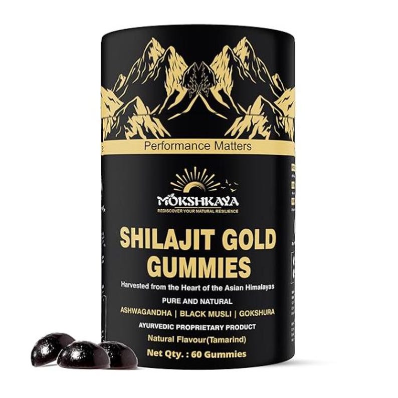 K&ouml;nnte beinhalten: Ein schwarzer zylindrischer Beh&auml;lter mit Shilajit Gold Gummies mit goldenen Berggrafiken und dem Text "Performance Matters". Das Etikett enth&auml;lt den Markennamen "Mokshkaya" und Details zum Produkt, einschlie&szlig;lich "Ashwagandha" und "60 Gummies". Drei dunkle Gummib&auml;rchen sind vorne.
