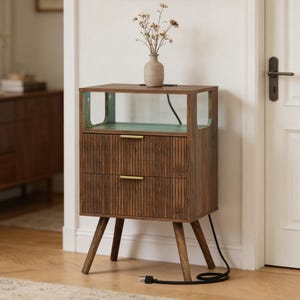 May include: A wooden nightstand with two drawers and a top shelf. The nightstand has a brown finish with vertical grooves on the drawer fronts and gold-colored handles. The top shelf has a teal-colored interior. A small vase with dried flowers sits on top.