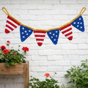 May include: A crochet banner featuring alternating red and white striped pennants and blue pennants with white stars. The banner is trimmed with gold yarn and is suitable for patriotic or holiday decor.