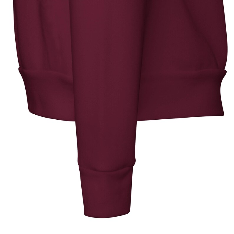 May include: Close-up of a maroon sweatshirt sleeve. The sleeve has a ribbed cuff at the wrist and a matching ribbed hem. The fabric appears to be a soft, comfortable material.