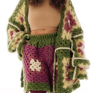 Puede incluir: Conjunto de cárdigan y shorts de ganchillo con diseño de cuadros de la abuela en verde, amarillo y morado. El cárdigan tiene mangas largas y cierre de lazo. Los shorts son de cintura alta. El conjunto es de estilo bohemio único.