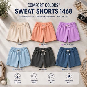 May include: Six pairs of Comfort Colors 1468 sweat shorts with drawstring waistbands, displayed in ivory, peachy, neon violet, hydrange, pepper, and blue jean colors. The text reads Comfort Colors Sweat Shorts 1468, Garment-Dyed, Premium Comfort, Relaxed Fit.
