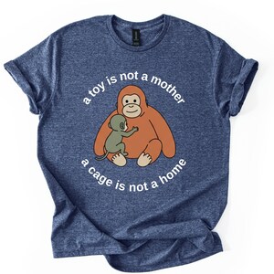 May include: Blue t-shirt with a graphic of an orangutan and baby orangutan. The text on the shirt reads "a toy is not a mother, a cage is not a home."