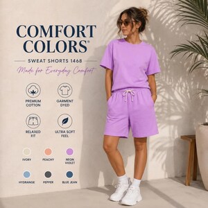 May include: A neon violet t-shirt and matching sweat shorts set featuring a drawstring waist. The text Comfort Colors Sweat Shorts 1468 Made for Everyday Comfort is visible along with icons for premium cotton, garment dyed, relaxed fit, and ultra soft feel.