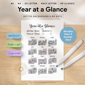 May include: A printable "Year at a Glance" calendar with a dotted background. The calendar includes all 12 months, with space to mark birthdays, events, time off, and important dates. Two white markers with blue and green tips are on the wooden surface.