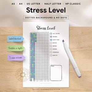 Könnte beinhalten: Ein weißer Planer mit der Aufschrift "Stress Level" und einem Raster zur Verfolgung des Stresslevels. Der Planer enthält farbcodierte Abschnitte für verschiedene Stresszustände und einen Notizenbereich. Ein weißer Marker mit lila Spitze liegt neben dem Planer.