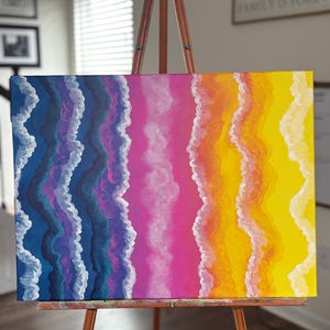May include: An abstract painting on canvas, displayed on a wooden easel. The artwork features vertical bands of colour: blue, purple, pink, orange, and yellow, with white wavy lines. The painting evokes a sense of a colourful sunset or ocean waves.