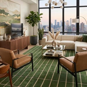 May include: A living room featuring a large green area rug with a white grid pattern, two tan leather armchairs with black metal frames, a cream-colored sectional sofa, a wooden media console, and a glass-topped coffee table with books.