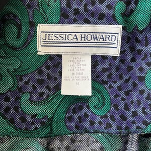 May include: Detail of a dress featuring a green, black, and purple paisley design. The label reads "JESSICA HOWARD" and includes fabric composition and care instructions. The dress is size 10.